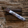 Brown leather keychain with a camouflage pattern on a wooden surface