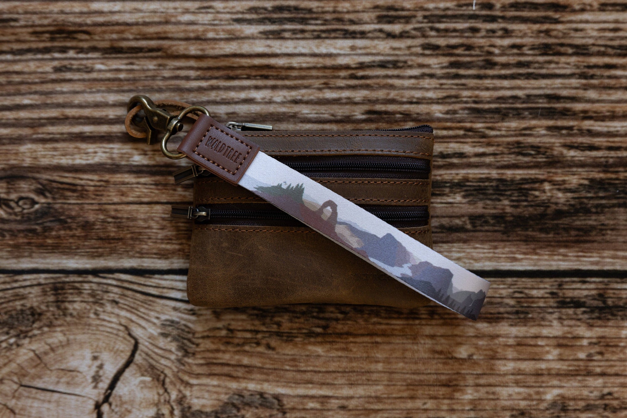 Brown leather keychain with a camouflage pattern on a wooden surface